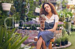 Looking for somebudy to love. a young florist using her smartphone to send a text.