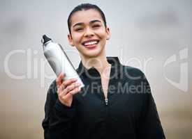 Stay hydrated. Cropped portrait of an attractive young female athlete holding her water bottle while standing outside.