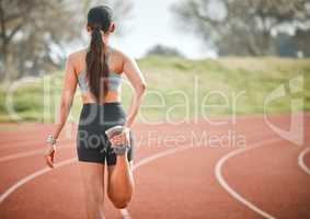 If I want to win, I have to prepare. Rearview shot of a young athlete stretching her legs on a running track outdoors.