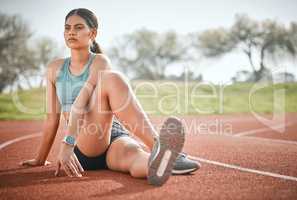Stretching properly can improve motion in your joints. a young athlete stretching her body on a running track.