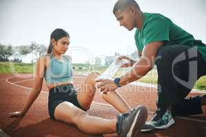 Youll need lots of rest in order to recover. a sports paramedic providing first aid to an athlete on a running track.
