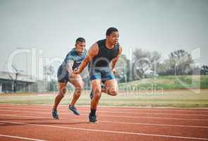 Hes done his part. Full length shot of a handsome young male athlete grabbing a baton from his teammate during a relay race.