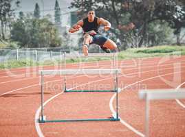 Making it look easy. Full length shot of a handsome young male athlete practicing hurdles on an outdoor track.
