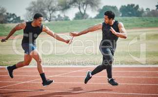 The perfect pass. Full length shot of a handsome young male athlete grabbing a baton from his teammate during a relay race.