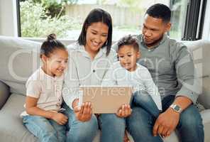 Lets call grandma. a young family happily bonding while using a digital tablet together on the sofa at home.