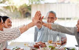 Well always be here to hold each other up. a family giving each other a high five while having dinner together at home.