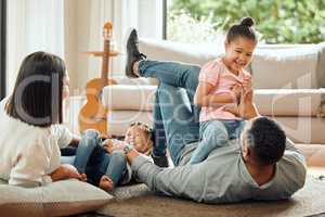 Them laughing is my favourite sound. a young family playing together on the lounge floor at home.