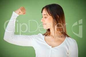 Personal challenges, public growth. Studio shot of a young woman showing her strong bicep against a green background.