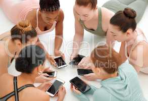 Fitness bloggers unite. a fitness group using their cellphones while in a circle.