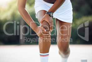 I wont be able to compete like this. Closeup shot of a sporty young woman experiencing knee pain while playing tennis outdoors.