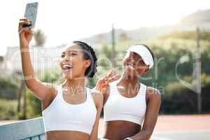We look exactly like winners. two sporty young women taking selfies together on a tennis court.