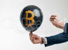 Appreciation and depreciation takes place within seconds. Studio shot of an unrecognisable businessman holding a pin to pop a balloon with a bitcoin symbol against a white background.