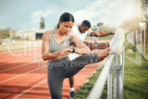 Warming up for a personal best. an attractive young female athlete checking her watch while warming up for her outdoor workout.