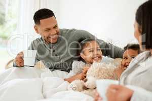 Mom tells the best stories. a beautiful young family talking and bonding in bed together.