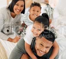 Hey, get off my back kid. Portrait of a beautiful young family talking and bonding in bed together.