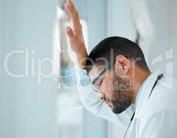 I might need a break. a young male doctor looking unhappy while at work at a hospital.