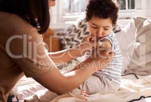 All soldiers have scars. a woman putting a plaster on her sons arm at home.