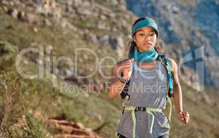 Hitting the trail on a regular can benefit your heart. a young woman running along a trail on the mountain.