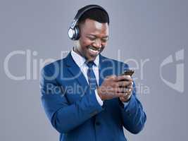 His favourite playlists in a single, convenient place. a handsome young businessman using his cellphone to listen to music in studio against a grey background.