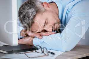 Ive dealt with enough deadlines for the day. a mature businessman sleeping at his desk in an office.