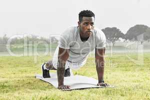 Hold it. Full length shot of a handsome young male athlete planking during his outdoor workout.
