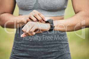 Looking for the time to beat. an unrecognizable young female athlete checking her smartwatch while exercising outside.