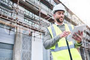 Success is a personal standard. a handsome male construction worker using a tablet while standing outside.