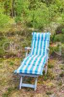 Outdoor garden lounge chair for relaxing, enjoying nature views on camping trip in remote woods, forest or environmental nature reserve. Seating furniture in serene, peaceful and secluded countryside