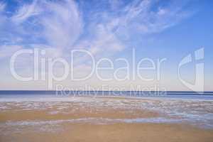 Blue ocean view of calm sea water on a summer morning. Nature landscape of a coastline with a blue sky and white clouds over the horizon. Seaside scene of tides and currents on a beautiful beach day
