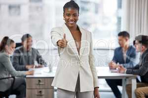 We aim to please. a young businesswoman showing a thumbs up while in a meeting at work.