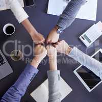 Taking a chance. a group of unrecognizable businesspeople giving each other a fist bump at work.