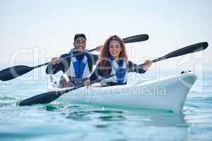 Outdoorsy couples will totally enjoy this. Portrait of a young couple kayaking together at a lake.