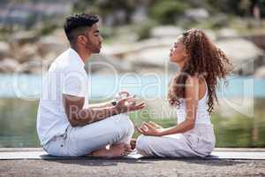 Yoga is at the center of their relationship. Full length shot of a young couple practicing yoga at the beach.
