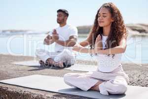 Embrace the quietness. Full length shot of a young couple practicing yoga at the beach.
