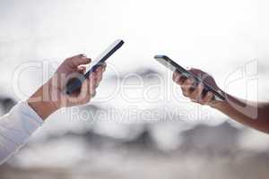 Theres always a connection to share in. Closeup shot of two unrecognisable women using cellphones outdoors.