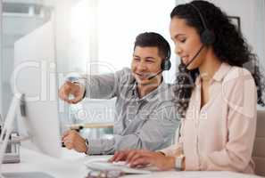 This is how you direct the caller. two call centre agents working together on a computer in an office.