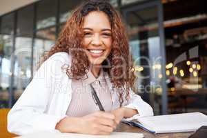 A diligent student. a young businesswoman writing in a notebook while at a cafe.