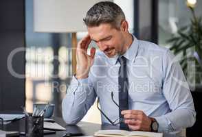 In need of fast effective relief. a mature businessman experiencing a headache while sitting at a desk in a modern office.