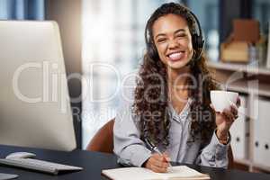 Setting up for the day. a young female call center worker enjoying a cup of coffee at work.