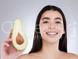 Why not use avocado for your own DIY facial mask. Studio portrait of an attractive young woman posing with an avocado against a grey background.