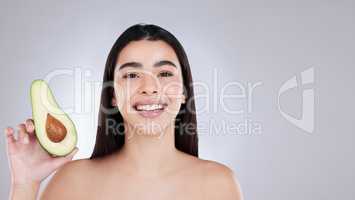 Avocados can boost skin and hair health in various ways. Studio portrait of an attractive young woman posing with an avocado against a grey background.