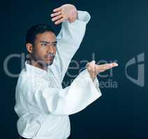 Mastering the art of self defense. a handsome young male martial artist practicing karate in studio against a dark background.