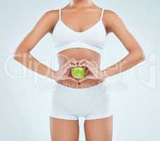 Eating better to reduce irritable bowel syndrome. an unrecognisable woman standing alone in the studio and posing with an apple.