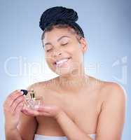 This scent is my happy place. Studio shot of an attractive young woman using using perfume against a blue background.