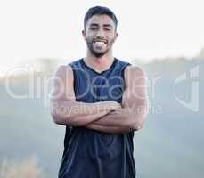 Time to get training. a handsome young man standing alone outside with his arms crossed after running.