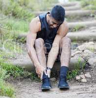 Ive sprained my ankle. Full length shot of a young man sitting alone outside and suffering from a twisted ankle during his run.