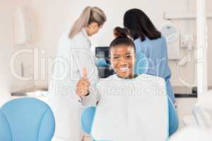 This is a great place to be. a young woman in her dentists office giving the thumbs up.