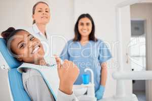 Time for an oral makeover. a young woman in her dentists office giving the thumbs up.