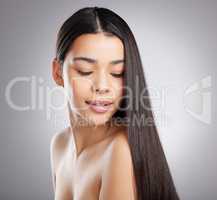 The haircare game is strong with this one. Studio shot of an attractive young woman posing against a grey background.