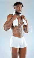Id rather sweat it out. Studio shot of a muscular young man posing with a towel around his neck.